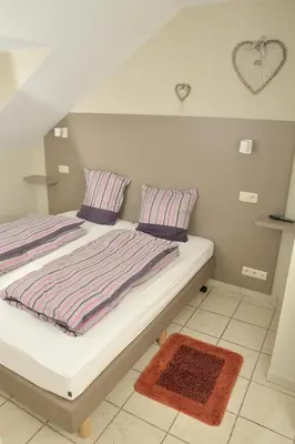 a bedroom with a bed with striped pillows and a rug at Holiday Home 't Regulierenhuisje in Tongeren