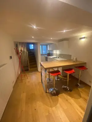a kitchen with a wooden table and red stools at TRIPLEX NEUVICE in Liège