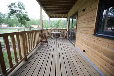 a wooden deck with a table and chairs on it at Recreatiedomein Warredal - The Lodge in Neeroeteren