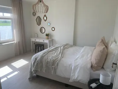 a white bedroom with a bed and a desk at Entre Deux Eaux in Lanaken