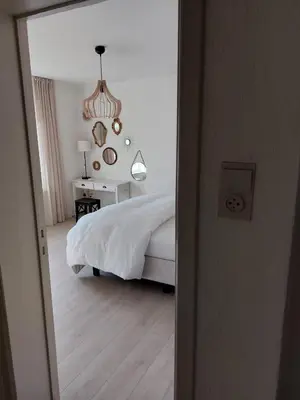 a bedroom with a bed and a table and a chandelier at Entre Deux Eaux in Lanaken