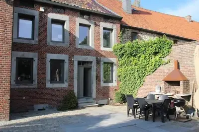 a brick house with a table and chairs in front of it at La maison de Barbara in Aubel