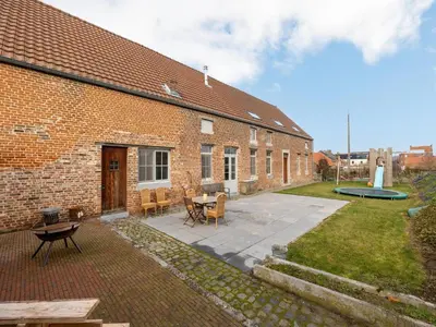 a brick building with a patio with a table and chairs at Riding School Farm Stay in Sint-Truiden