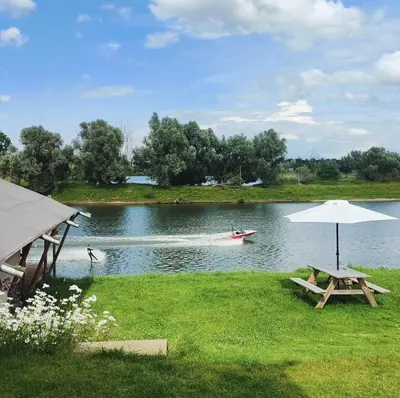 a boat on a lake with a picnic table and an umbrella at Camping de Boomgaard in Maaseik