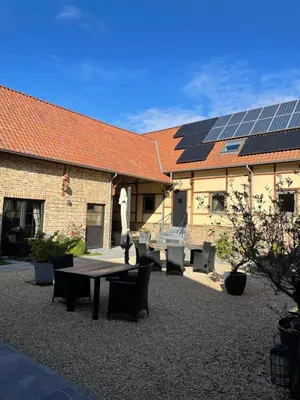 a patio with a table and chairs and a building with solar panels at Hoeve Lavigne in Wellen