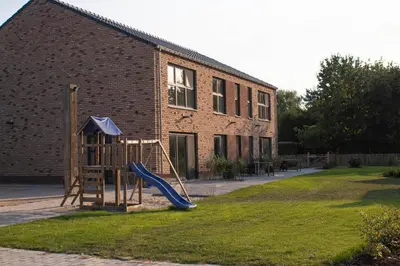 a playground in front of a brick building with a slide at De Hoog Velden 14 in Pelt