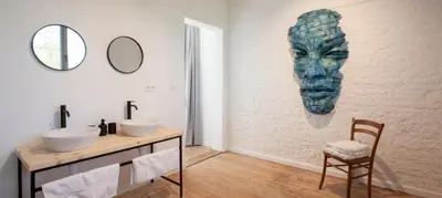 a bathroom with two sinks and a painting of a face at Le Charbonnage in Genk