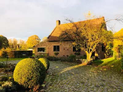 a brick house with a tree in front of it at B&B De Paenhoeve in Eksel