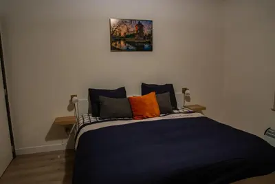 a bedroom with a blue bed with orange pillows at Kanaalzicht21 in Hasselt