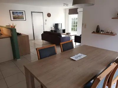 a dining room and living room with a wooden table and chairs at Kanaalzicht21 in Hasselt