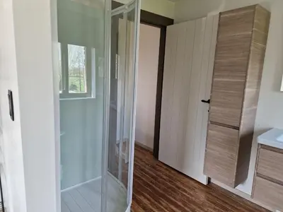 a glass shower in a bathroom next to a door at Gîte Eschen in Plombières