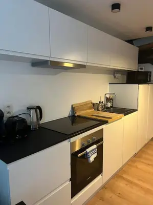 a kitchen with white cabinets and a black counter top at Triplex d'architecte en hypercentre in Liège