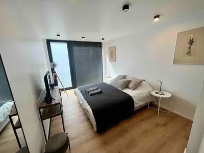 a bedroom with a bed and a large window at Triplex d'architecte en hypercentre in Liège