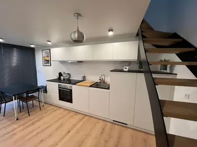 a kitchen with white cabinets and a table and a staircase at Triplex d'architecte en hypercentre in Liège