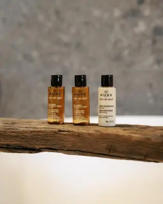 three bottles of essential oils sitting on a wooden shelf at Domaine des Thermes in Awans