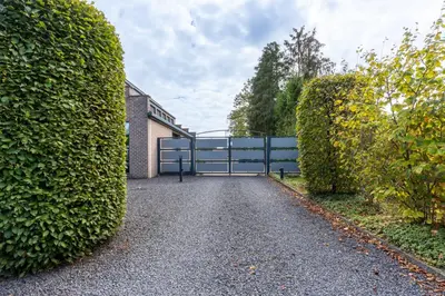 a driveway with a gate between two large bushes at B&B Tabibito in Genk