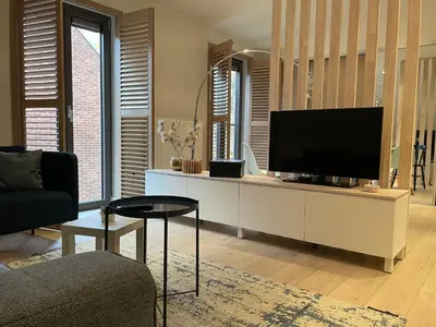 a living room with a flat screen tv on a white cabinet at Bonne Suite Chambre d'Hotes in Rekem