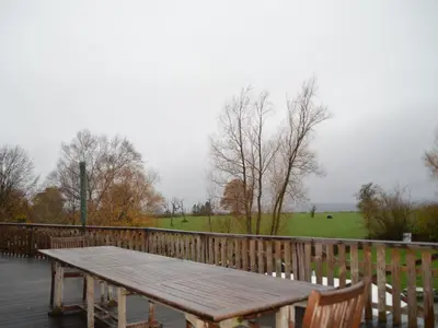 a wooden picnic table on a deck with a fence at Verviers Villa with Sauna in Verviers