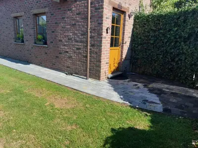 a brick building with a yellow door and a yard at Ô Baguenaudes in Jalhay