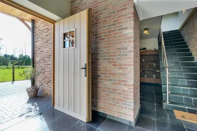 an open door in a brick wall with a staircase at Franciscushof in Pelt