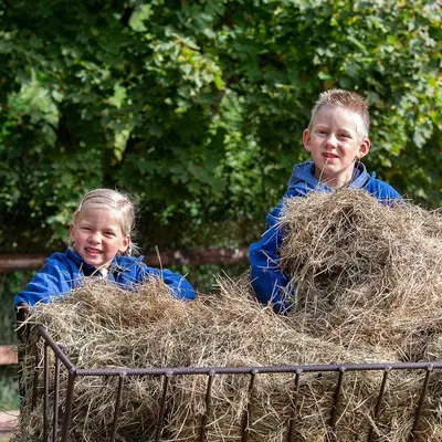 two children are sitting in a cart of hay at Franciscushof in Pelt