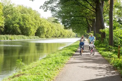 a group of people riding bikes down a path next to a river at Franciscushof in Pelt