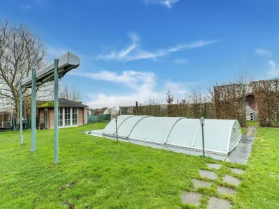 a large white greenhouse in a grass field at Zoutleeuw Home with Pool in Zoutleeuw