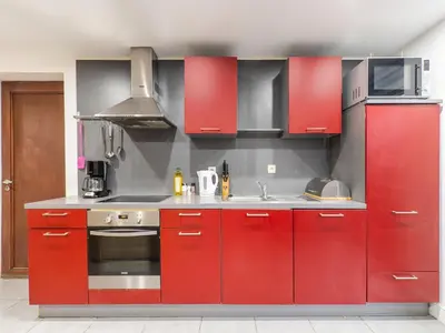 a kitchen with red cabinets and a sink at Zoutleeuw Home with Pool in Zoutleeuw