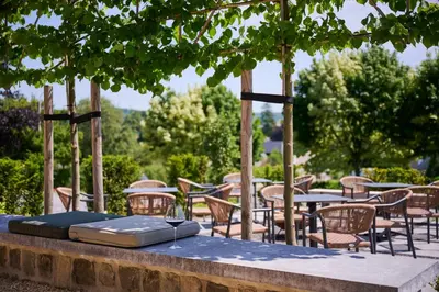 a table with a glass of wine on it under a tree at La belle Maison in Sippenaeken