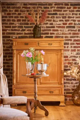 a table with flowers on top of a wooden cabinet at La belle Maison in Sippenaeken