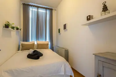 a bedroom with a white bed with a window at Leopold Appartementen & studio's in Sint-Truiden