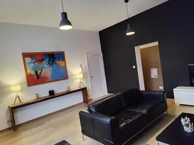 a living room with a black leather couch at Leopold Appartementen & studio's in Sint-Truiden