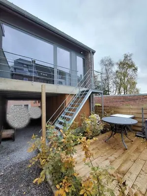 a house with a balcony and a table on a deck at Aux six fontaines in Herve