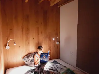 a young boy laying in bed with a tablet at Lodge op de Berg in Bree