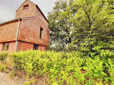 an old brick building with a tower next to trees at Lodge op de Berg in Bree