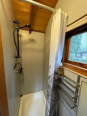 a bathroom with a shower with a shower curtain at Pipowagen de Kat in de Hoge Kempen nabij Maastricht in Lanaken