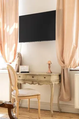 a desk with a chair and a television on a wall at Huis van Loon in Borgloon