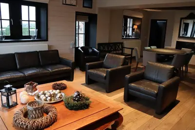 a living room with leather furniture and a table at Country house Clos des hortensias in Blégny