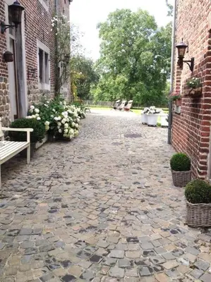 a stone walkway with a bench and a brick building at Country house Clos des hortensias in Blégny