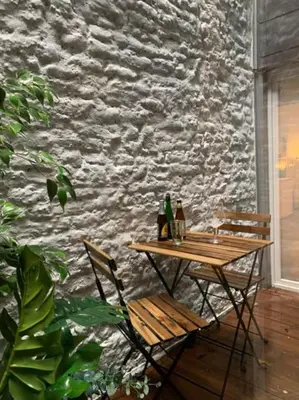 a wooden table and chairs next to a stone wall at Mr White's in Liège