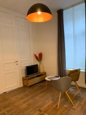 a living room with a tv and a chair and a table at Mr White's in Liège