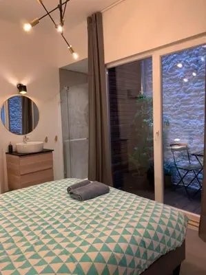 a bedroom with a bed and a bathroom with a window at Mr White's in Liège
