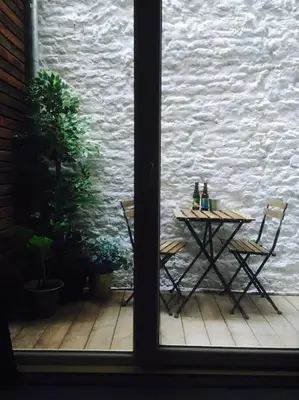 a table and chairs on a patio with a window at Mr White's in Liège