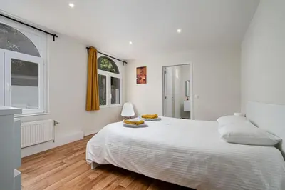 a white bedroom with a large bed and a window at Amazing appartement à Liège avec jardin in Liège