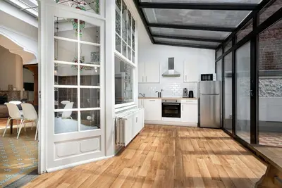 a kitchen with white cabinets and a hard wood floor at Amazing appartement à Liège avec jardin in Liège