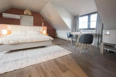 a bedroom with a bed and a table and chairs at Logies Op 't Gestel in Oudsbergen