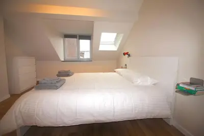 a bedroom with a large white bed with a window at Appartement 3 chambres en plein centre ville in Liège