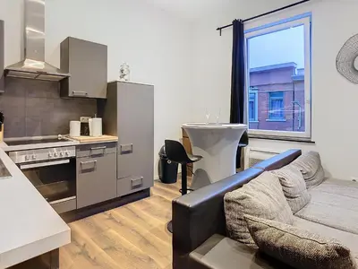 a living room with a couch and a kitchen at Appartement 021 in Liège