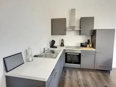a kitchen with white counters and a sink and a stove at Appartement 021 in Liège