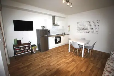 a living room with a table and a kitchen with a table and chairs at Bel appartement 2 chambres avec terrasse in Liège